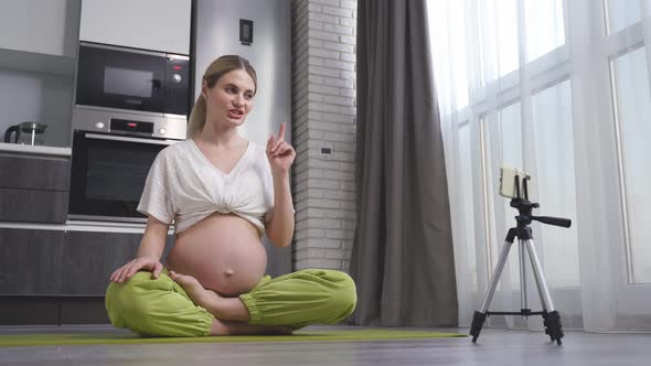 Pregnant Woman Sitting in a Lotus Position on the Floor Ready for Prenatal Yoga Exercises in Sports