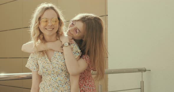 Two young beautiful smiling hipster girls in trendy summer sundress alt
