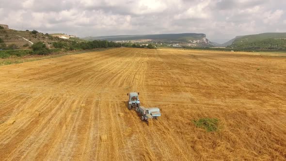 Tractor Rides in the Field with the Harvested Crop Bird's-eye