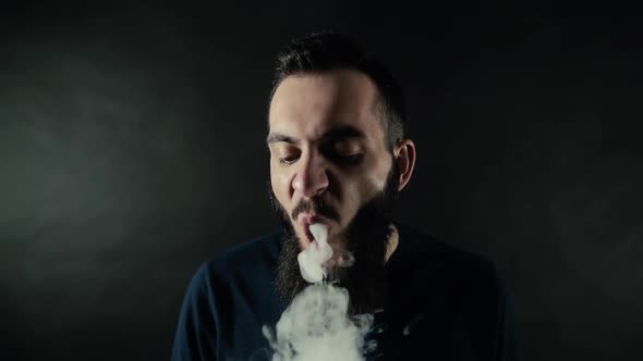 Close-up Portrait of Bearded Man Vaping Many Small Steam Circles To Camera alt