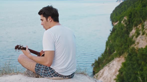 Young Man Playing Ukulele and Singing  Sitting on the Mountain alt