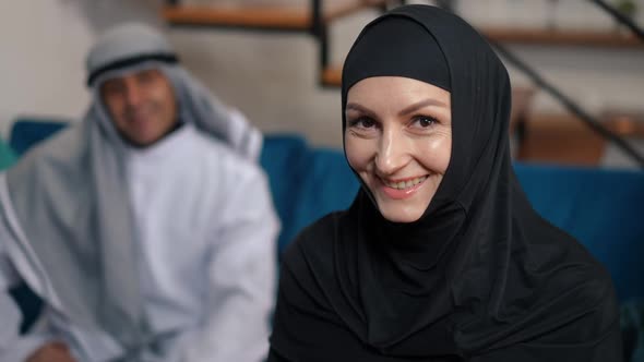 Portrait of Happy Charming Middle Eastern Woman in Black Hijab Looking at Camera Smiling and Looking alt