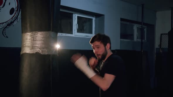 Alone Boxer Hits Punching Bag in Dark Gym in Slow Motion alt