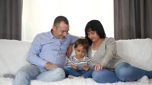 Father, Mother and Son Spend Time Together Watching a Movie on a Tablet. The Concept of a Happy alt