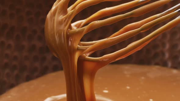 Melted caramel dripping from whisk, closeup food shot. 