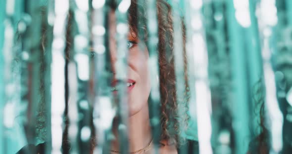 Intriguing curly girl dancing through a glitter curtain alt