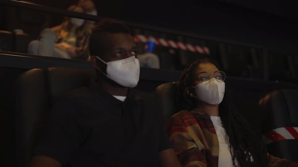 African American Couple Enjoying Film During Pandemic Wearing White Face Masks alt