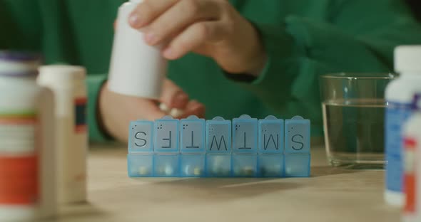 Man Fills an Organizer with Pills