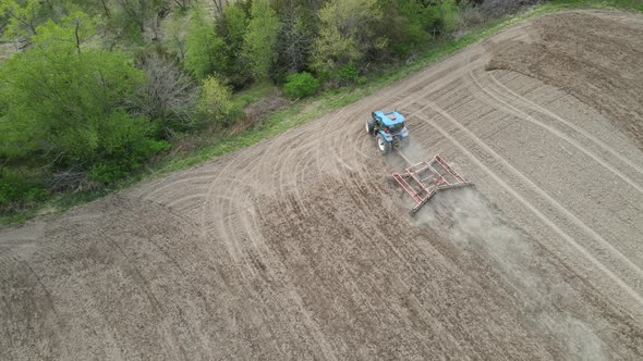 Bird eye view of farmer tilling dirt field in methodical rows, slowly turning at the end of the row.