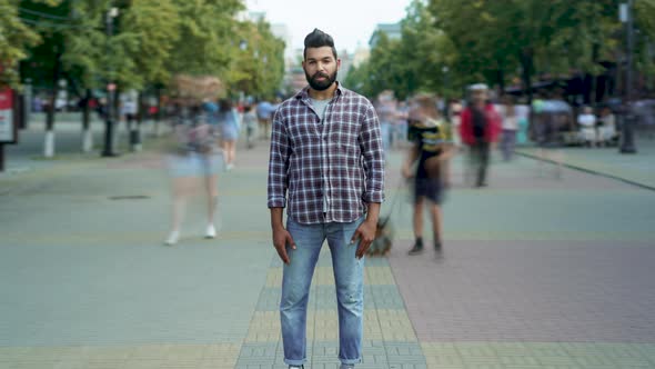 Zoomin Time Lapse Portrait of Attractive Middle Eastern Man Standing Alone Among People Passing By alt
