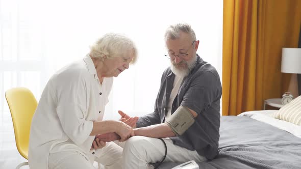 Mature Woman Controlling Blood Pressure of Husband Using Tonometer