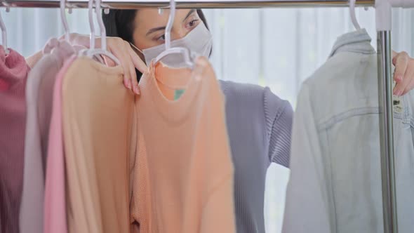 Young girl entrepreneur searching and choosing clothe on clothes rack for online selling at home. alt