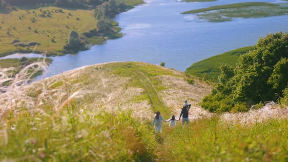 Young Happy Family Walking Down the Hill To the River alt