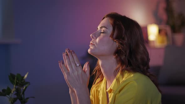 Woman Believing in God Prays with Folded Hands in Love on Her Knees in Evening in Room Before alt