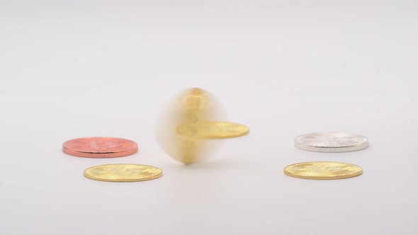 A man spins a real gold metal bitcoin among other crypto currencies coins isolated on white. alt