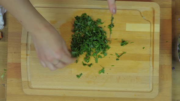 Woman Chopping Parsley at Wooden Kitchen Table