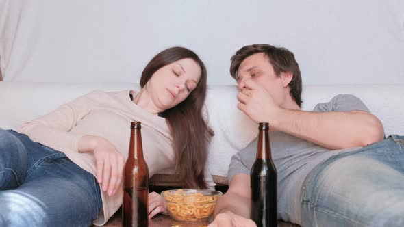 Couple of Young Man and Woman Eating Chips Drinking Beer and Watching TV