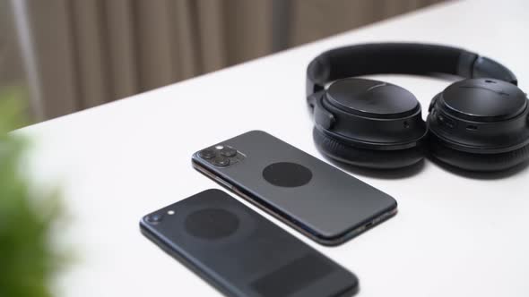 close up video of two dark smartphone and headphones on a white table alt