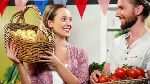 Couple interacting while holding vegetables in basket alt