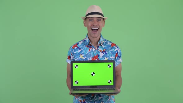 Happy Multi Ethnic Tourist Man Showing Laptop and Looking Surprised alt