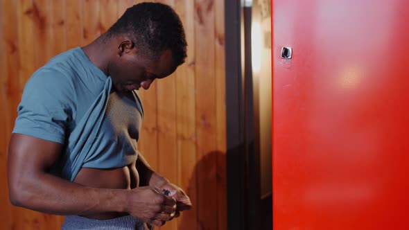 Africanamerican Athletic Young Man Tying Up His Shorts in the Locker Room alt