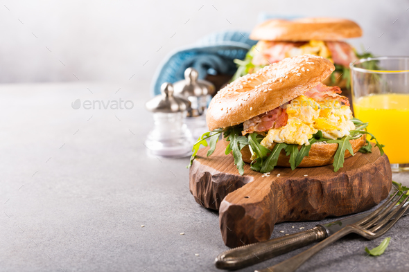Bagels with scrambled eggs, rucola and fried bacon - Stock Photo - Images