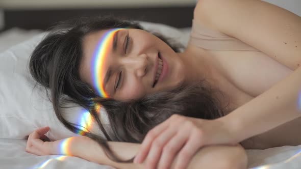 Pretty Mixed Race Woman Waking Up and Smiling in the Morning. Rainbow Flare on Her Face. Beauty and