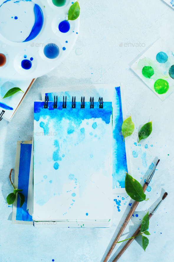 Drawing spring concept with artist tools, green and blue watercolor  sketchbooks, brushes and color Stock Photo by dinabelenko