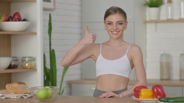 Sporty Woman Showing Thumbs Up While Standing in Kitchen alt