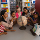 Front view of female teacher teaching the kids about the globe at table in school library - $5.00 Front view of female teacher teaching the kids about the globe at table in school library