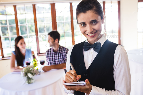 Portrait of waitress writing order on notepad in restaurant