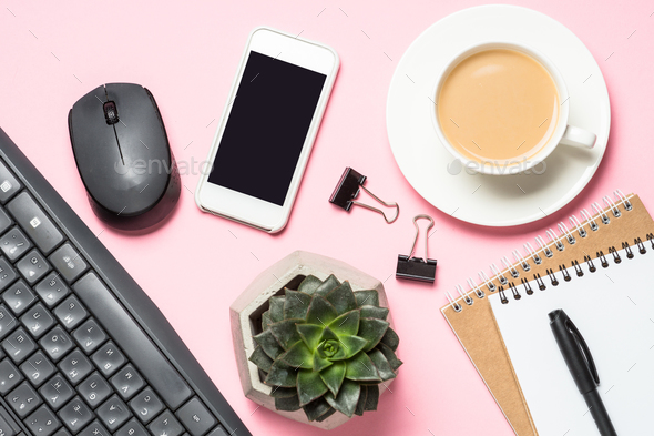 Freelance workplace with notepad, coffee cup, succulent and mouse on pink