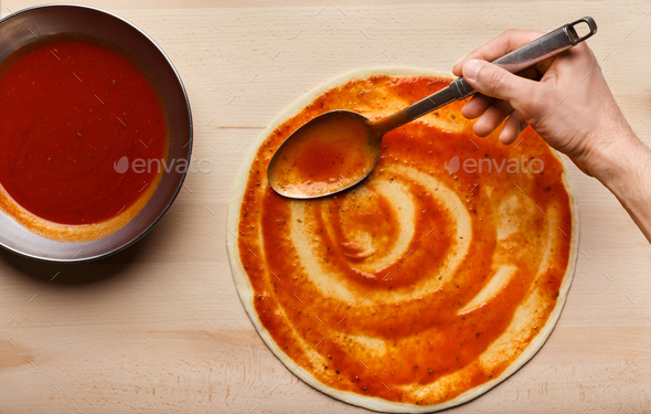 Download Chef hand spreading tomato paste on pizza base Stock Photo ...