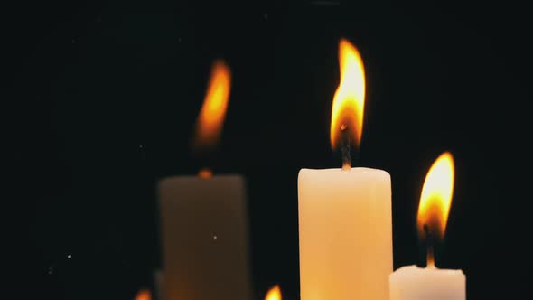 White Paraffin Candles with a Yellow Tint Burn on Black Background in Reflection alt