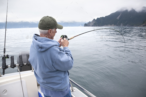 Senior fisherman catching a fish in the ocean near Seward, Alaska
