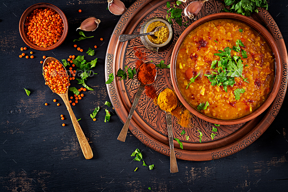 Indian Dhal spicy curry in bowl, spices, herbs, rustic black wooden background.
