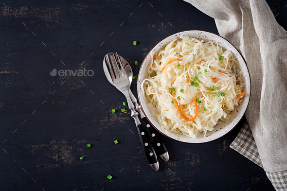 Fermented cabbage. Vegan food. Sauerkraut with carrot and spices in bowl on the dark background. - Stock Photo - Images