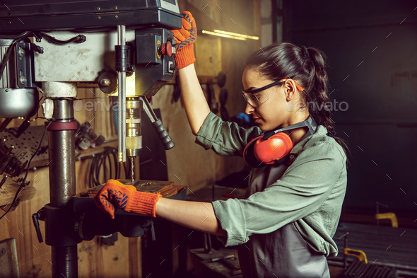 Busy and serious craftswoman grinding timbers with special machine. - Stock Photo - Images