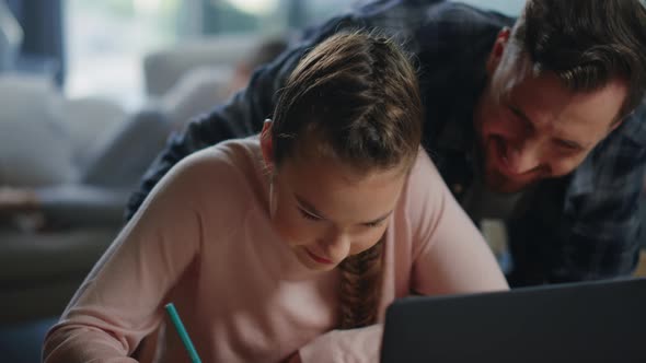 Daughter Studying Remotely Under Father Supervision. Girl Writing Notebook. alt