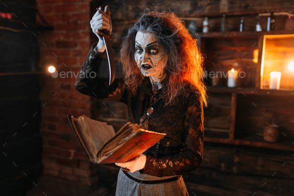 Scary witch holds spellbook and knife - Stock Photo - Images
