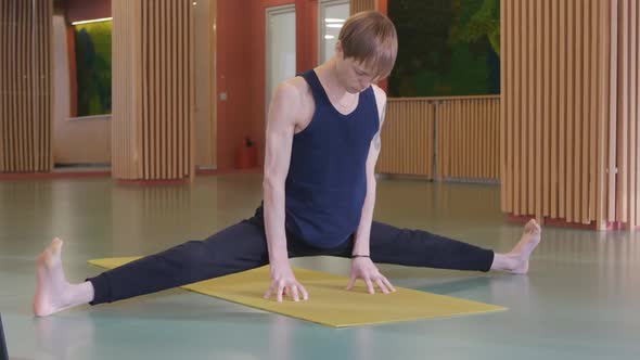 a Young Caucasian Man Is Doing Yoga in an Empty Hall