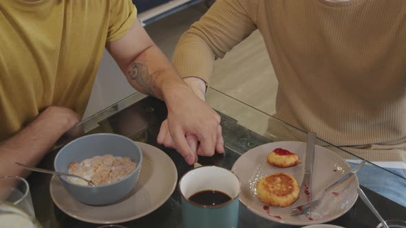 Unrecognizable Men Holding Hands during Breakfast alt