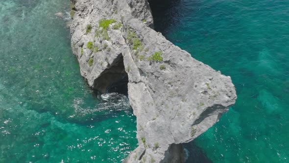 Cinematic shot of famous rock arch on Nusa Batupadasan at Atuh Beach, aerial alt