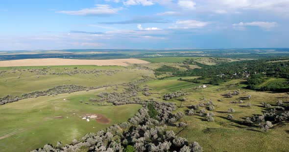 Panoramic View Of The Green Terrain Of The Hills With Lush Vegetation Under Cloudy Blue Sky. aerial alt