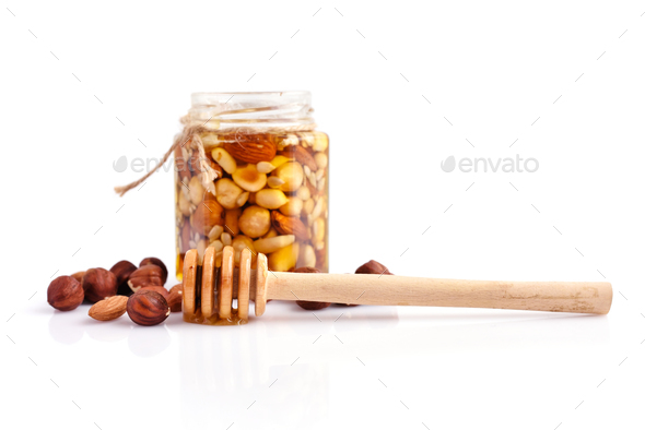 A honey jar with a spoon for honey and different nuts on white b Stock  Photo by Nataljusja