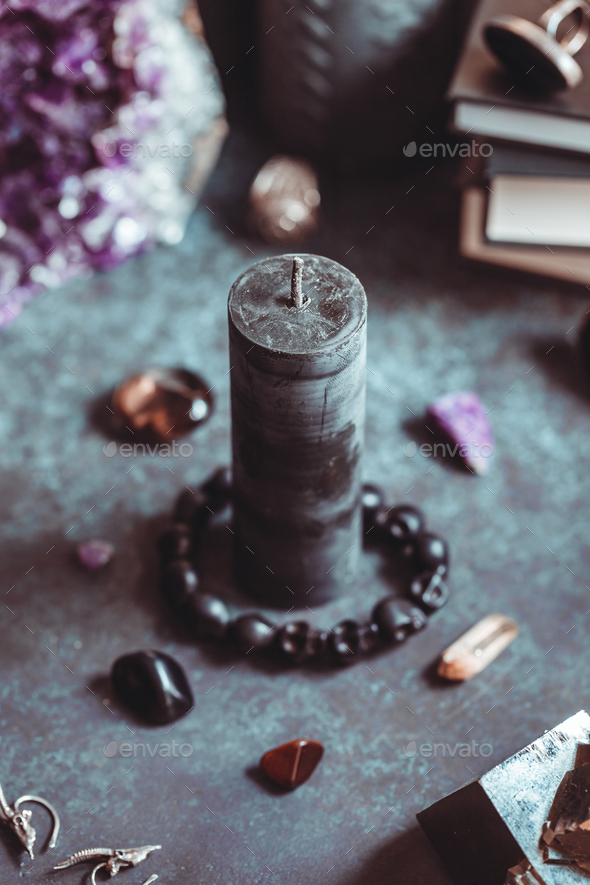 Black candle on a witch's altar for a magical ritual among crystals and ...