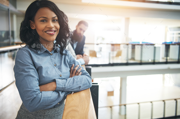 Smiling young businesswoman standing in the hallway of an office - Stock Photo - Images