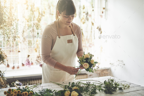 Female florist arranging flowers at a table in her shop