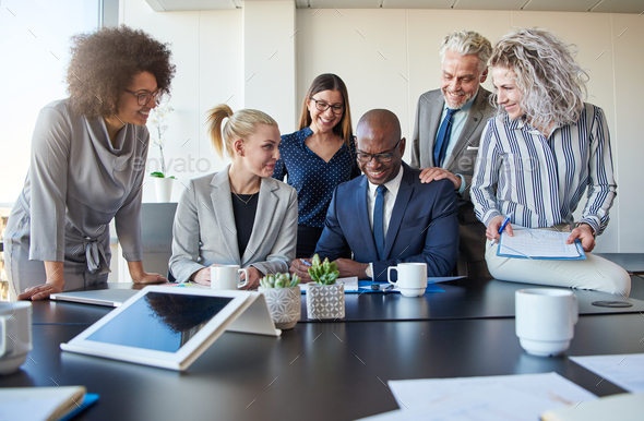Smiling colleagues working together at a table in an office - Stock Photo - Images