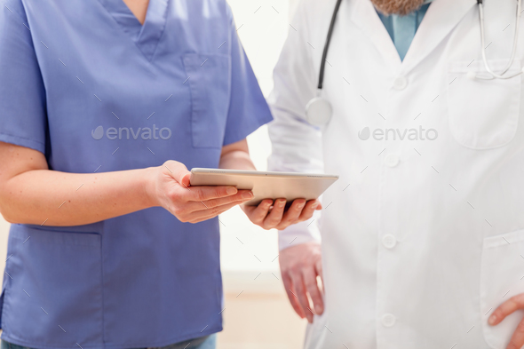 Doctors discussing report about a patient at tablet computer in hospital - Stock Photo - Images